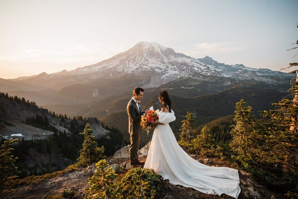 Couple exchanging vows on a mountaintop at sunset with Mount Rainier in the background
