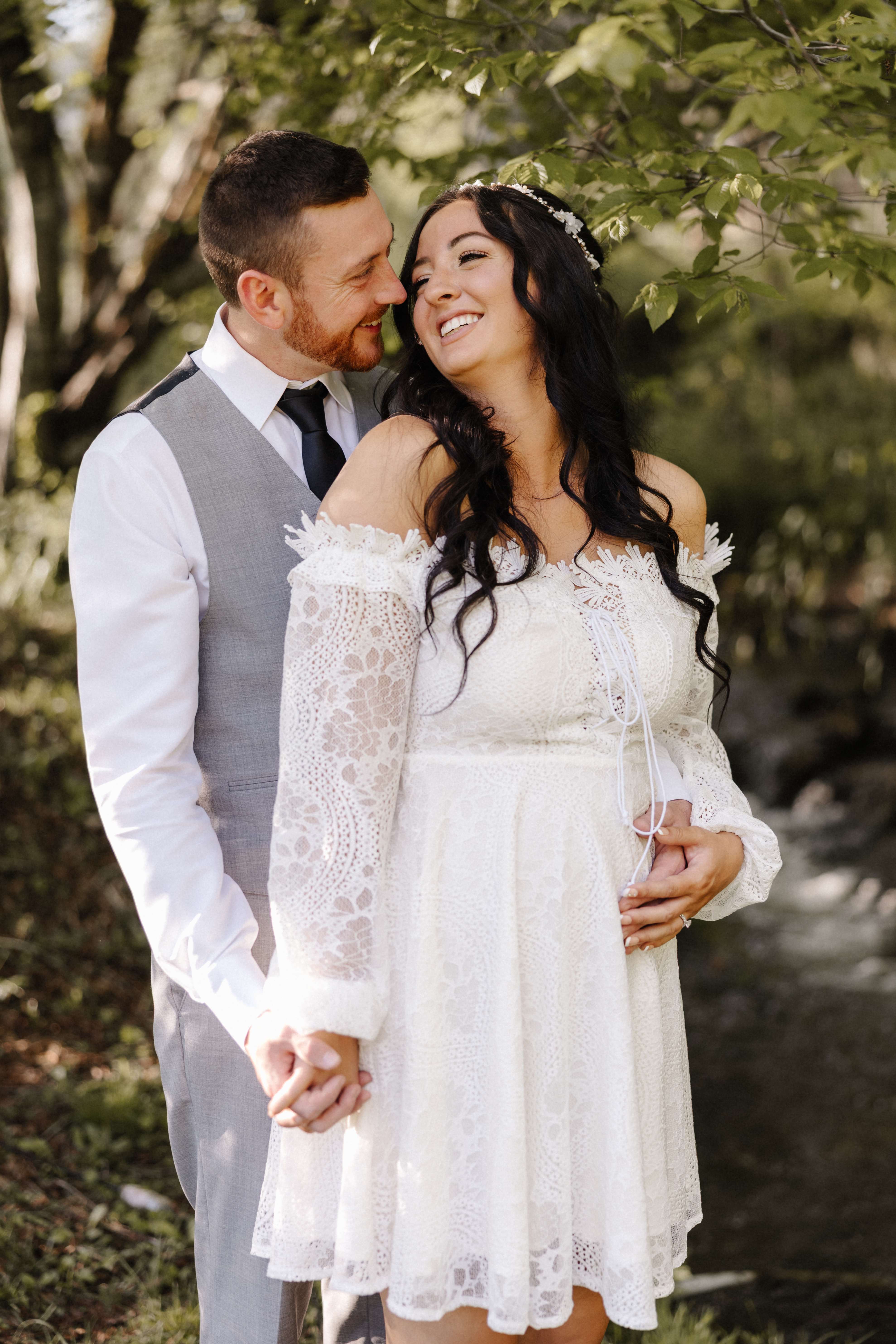 Bride and groom smiling at each other in a sunlit forest