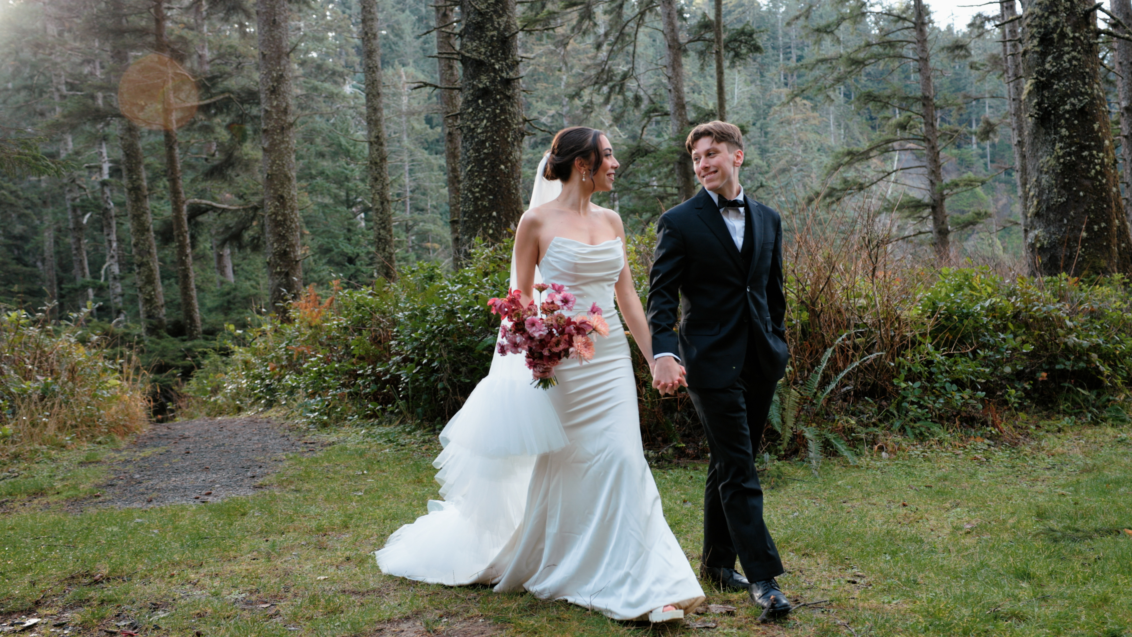 Bride and groom walking hand in hand through a forest
