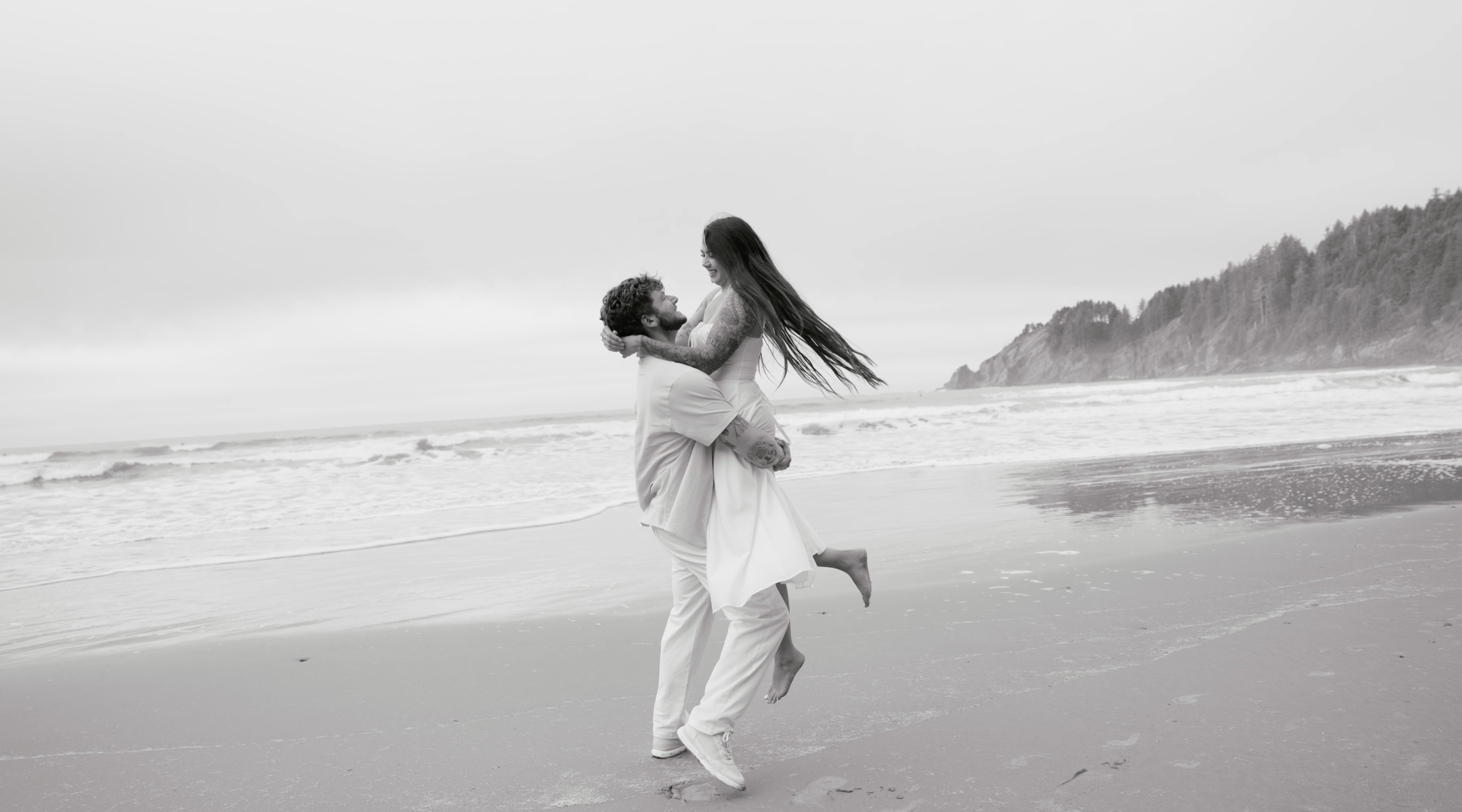Man lifting woman on beach, black and white